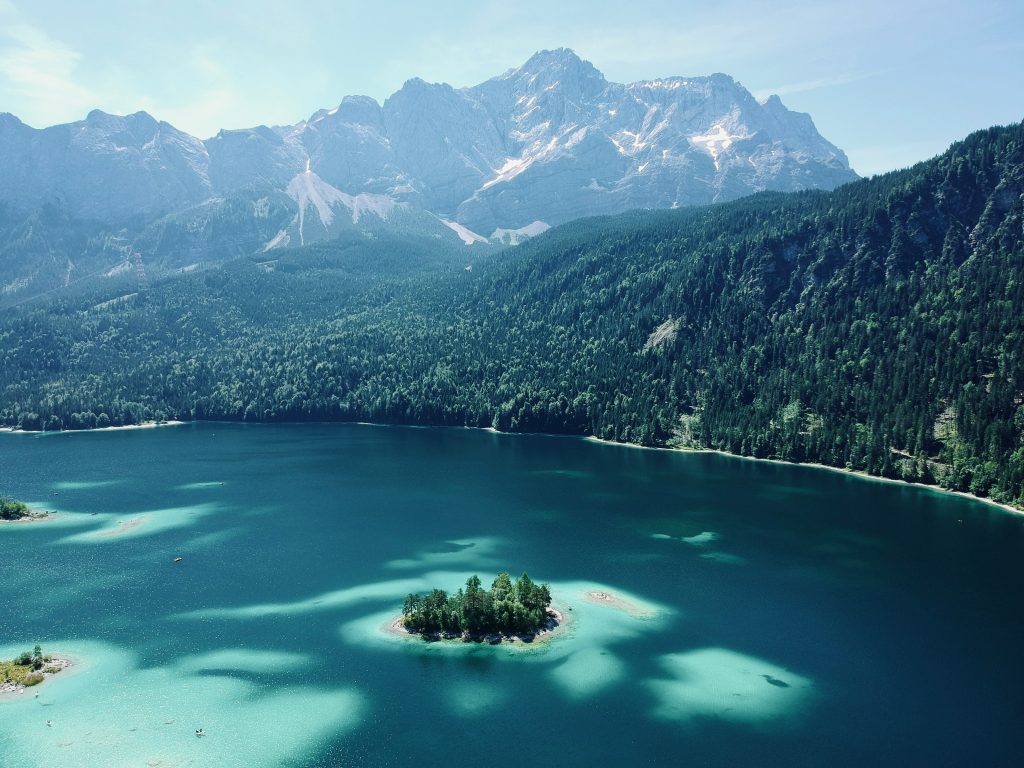 Eibsee Rundweg – Luftaufnahme des türkisfarbenen Eibsees mit kleiner Insel und der Zugspitze im Hintergrund.