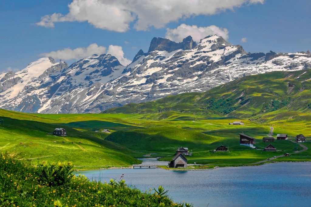Hüttenwanderung mit Kindern in den Alpen: Familie wandert auf leichtem Bergweg zu einer Hütte vor Alpenpanorama